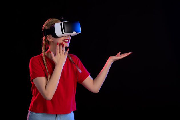 年轻女性年轻女性在黑暗中玩虚拟现实游戏超声波视觉正面图虚拟现实姿势游戏