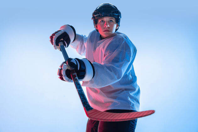 动作年轻人年轻的男性冰球运动员 在霓虹灯下 背景是白色的棍子运动员戴着设备和头盔练习运动的概念 健康的生活方式 运动 运动 动作比赛团队合作健康