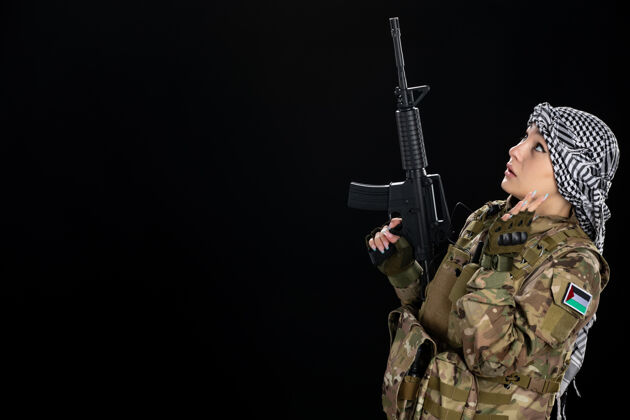 战士穿军装的女兵在黑墙上拿着步枪战争士兵步枪