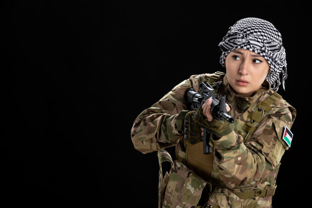 武器穿军装的女兵把机关枪对准黑墙上战争军队枪