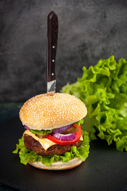 模糊特写镜头刀在美味的肉三明治和绿色的黑色托盘在左侧的模糊表面与自由空间快餐食品肉三明治奶酪