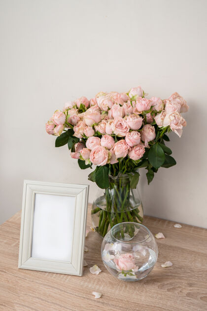 玻璃木桌上的肖像白色相框模型现代玻璃花瓶 带有玫瑰白墙斯堪的纳维亚内饰木头花空白