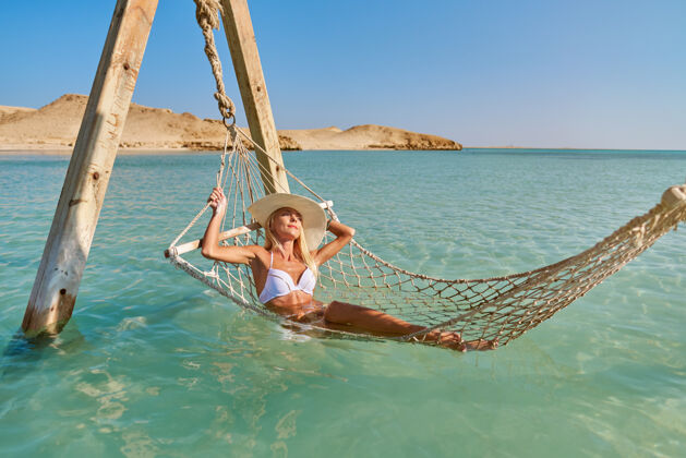 海滩旅行和度假的概念妇女放松吊床在海上休闲女人享受
