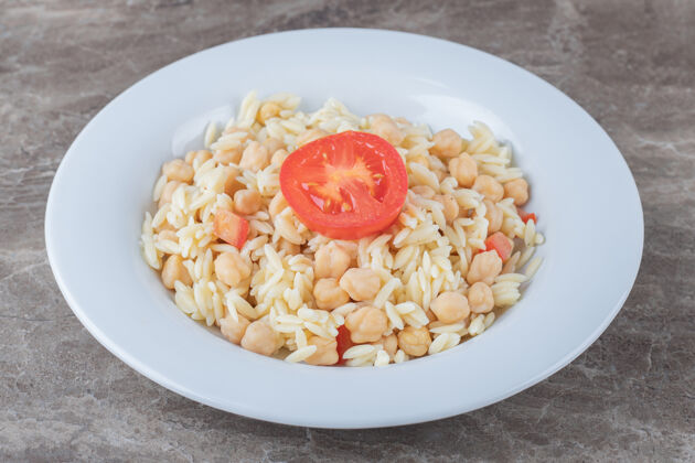 有机鹰嘴豆和意大利面 在大理石板上放上番茄片美味意大利面营养