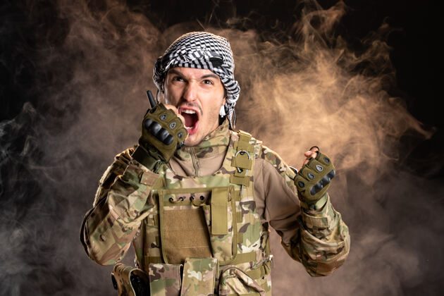 军装一名巴勒斯坦士兵在黑暗的墙上尖叫着穿过无线电台武器军队黑暗