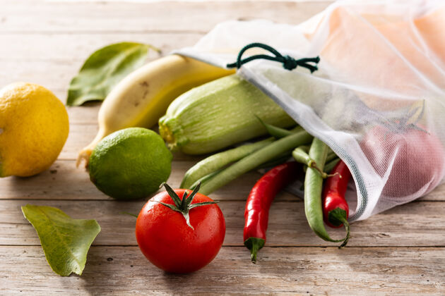 蔬菜环保的可重复使用的购物袋与蔬菜和水果在木桌上酸橙绿豆生的