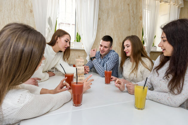 微笑朋友们一起喝果汁 在咖啡馆玩塔式游戏聚会詹加竞争