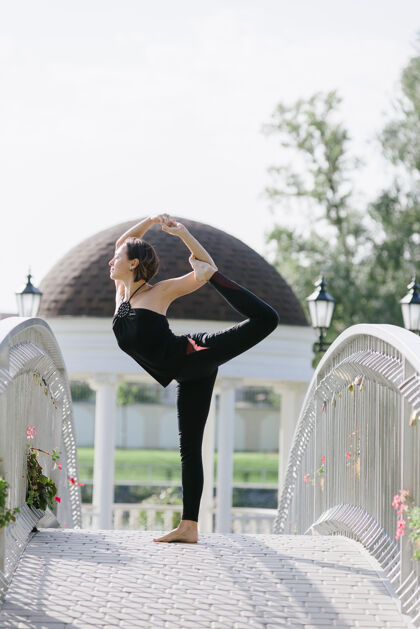 锻炼一位女瑜伽士夏天在公园的桥上做体式免疫力训练和谐