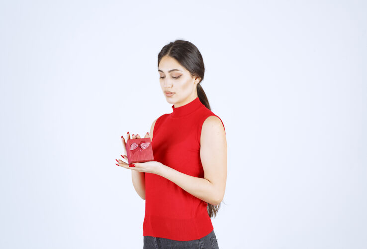 女人穿红衬衫的女孩展示她的红色礼盒工人职员服装