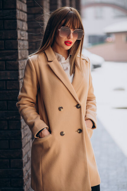 服装穿着米色外套的年轻漂亮女人在街上摆姿势街头城市城市