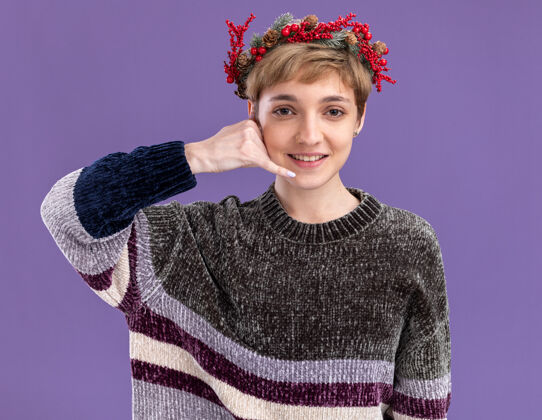 穿微笑的年轻漂亮女孩戴着圣诞花环在紫色的墙上做着孤立的呼叫手势花环微笑年轻
