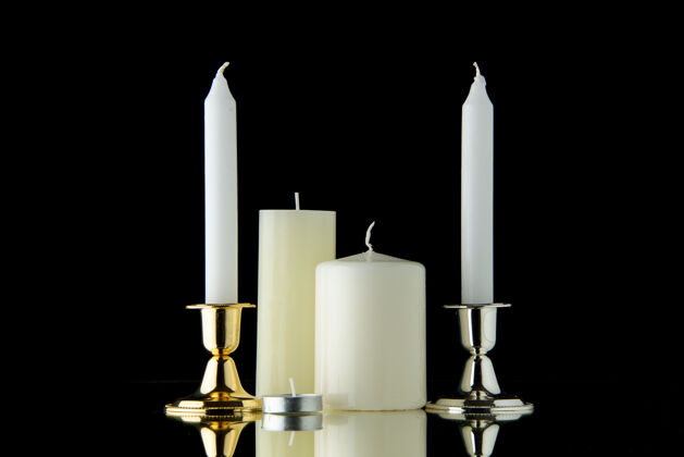 烛台黑漆漆上白色蜡烛的前视图纪念光葬礼