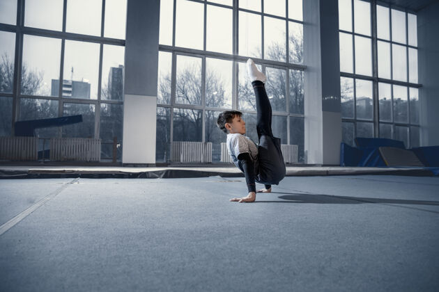 儿童小男体操运动员在健身房训练 灵活和活跃白种人适合小男孩 运动员在运动服练习力量 平衡运动 动作 运动 动态概念男孩健康自信