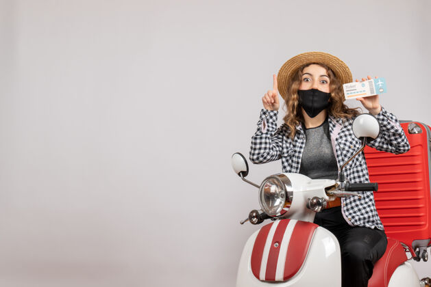 滑板车正面图：坐在轻便摩托车上的年轻女孩提着手提箱拿着票轻便摩托车旅行者旅行