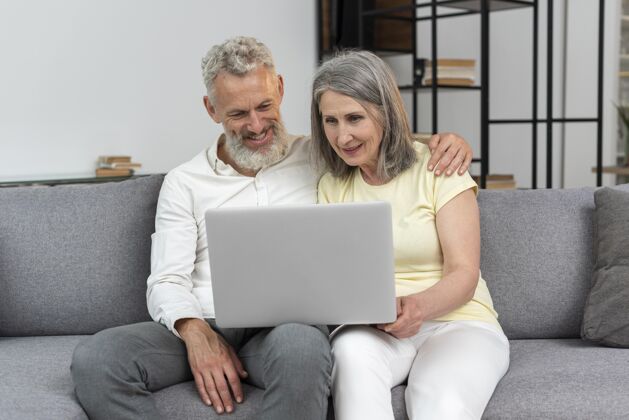 成熟老两口在家沙发上用笔记本电脑养老金胡须女人
