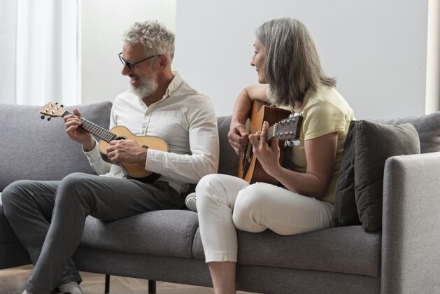 老年人资深夫妇在家学习吉他和四弦琴课程的笔记本电脑老年人灰色头发成人