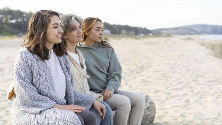 团结妈妈和她的两个女儿一起在沙滩上度过时光妈妈女人女人
