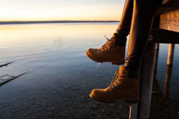 日出日落时分 穿着靴子坐在码头上的年轻女孩日落女人靴子