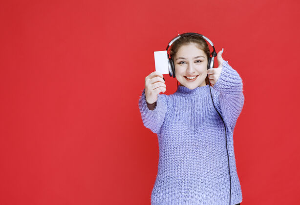 人类戴着耳机的女孩出示名片 做着满意的手势模特音乐休闲