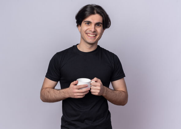 市民面带微笑的年轻帅哥穿着黑色t恤拿着一杯咖啡隔着白墙姿势咖啡抱着