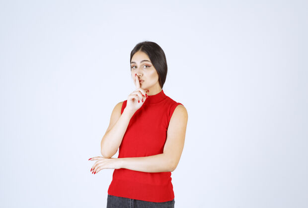 年轻人穿红衬衫的女孩指着自己的嘴 要求安静服装雇员女性