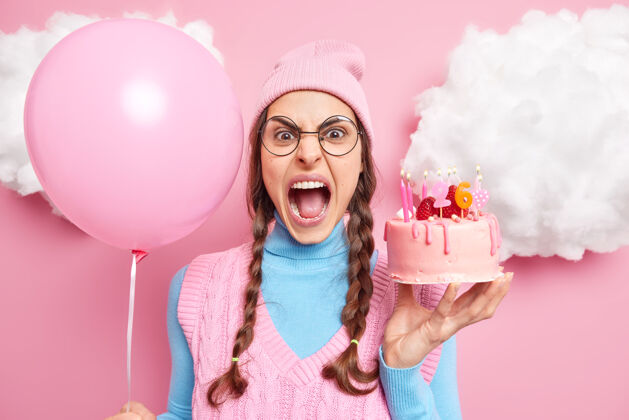 可爱女人大声尖叫 张大嘴巴 因为有什么东西而生气 拿着充气气球和生日蛋糕表达消极情绪庆祝的概念蜡烛小吃生日