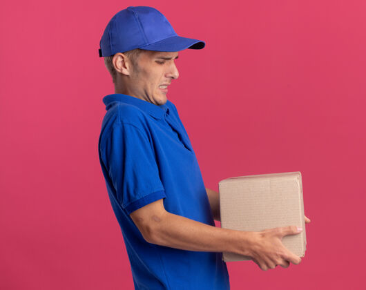金发年轻的金发送货员站在一边 手里拿着沉重的名片盒送货粉色Cardbox