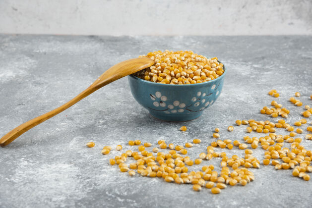 内核用木勺把生玉米粒放在蓝碗里种子谷物天然