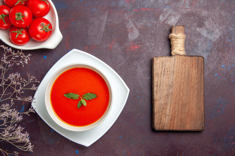 视图俯瞰美味的西红柿汤配上新鲜西红柿的深色背景菜酱汁西红柿色一餐汤新鲜午餐容器