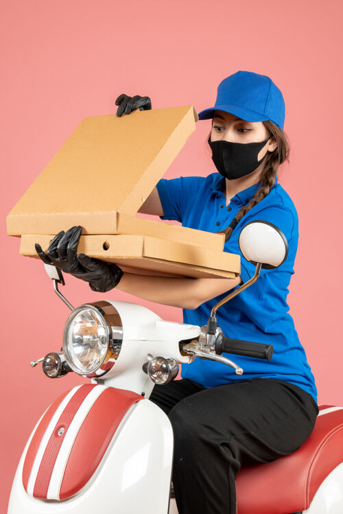 盒年轻自信的女快递员戴着医用口罩和手套打开粉彩桃盒子的垂直视图信心人工作