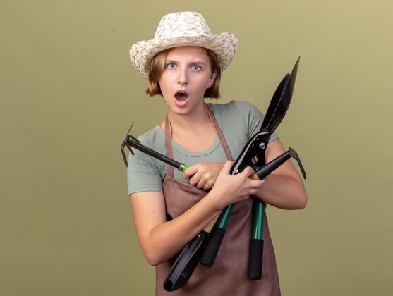年轻兴奋的年轻斯拉夫女园丁戴着园艺帽拿着园艺工具花园园艺绿色