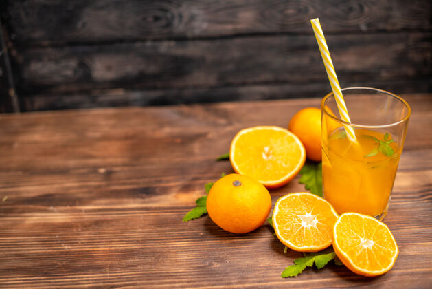 薄荷新鲜橙汁的俯视图 在木桌的左侧有一个装有薄荷管和整个切好的橙子的玻璃杯壁板柑橘管