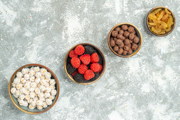 不同的糖果顶视图不同的糖果和葡萄干在浅白色背景糖糖茶封茶胡椒基地