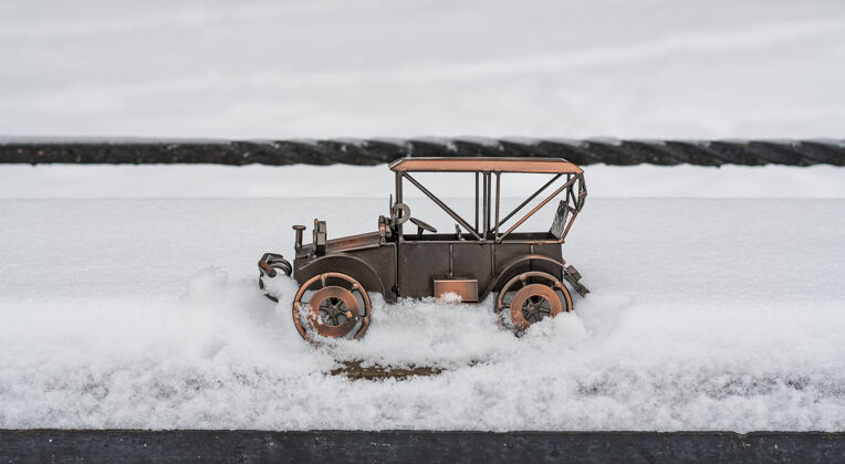 旧的一辆复古汽车的玩具模型陷在公园街道的雪地里天气设备机械