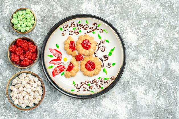 陶瓷器皿顶视图美味饼干与红果冻和糖果浅白色背景饼干蛋糕饼干甜茶食物陶器茶