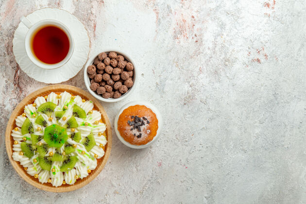 晚餐俯瞰美味的甜点与切片猕猴桃和一杯茶的白色背景饼干奶油水果甜点糖果蛋糕蔬菜餐糖果