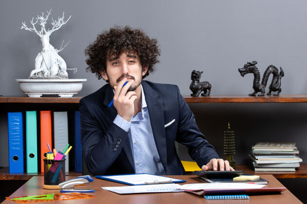视图正面图有魅力的年轻商人坐在办公室的办公桌上个人电脑公司