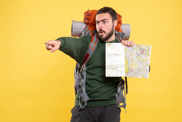 商务顶视图年轻的愤怒旅行的家伙背着背包拿着地图 指着黄色的前方专业年轻肖像