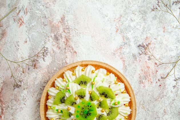 鲜花顶视图美味的猕猴桃甜点 带有美味的白色奶油和切片水果 背景为浅白色甜点蛋糕奶油水果热带水果健康香草