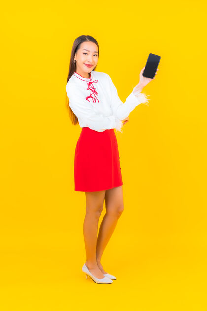 在线用黄色的智能手机描绘美丽的亚洲年轻女子肖像欢呼女性