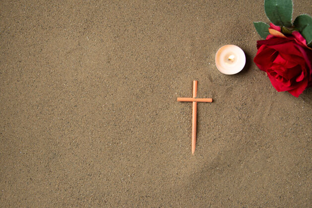 红色沙滩上有红花的棍棒十字架俯视图纹理死亡花
