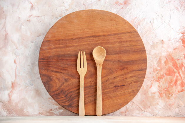 晚餐圆形木质砧板和汤匙的正面图 站在五颜六色的表面上用具立场刀