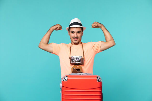 成人带着红色手提箱和蓝色相机的度假男人蓝色旅行包