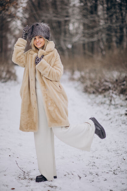 旅程美丽的女人在满是雪的公园里散步树休闲毛衣