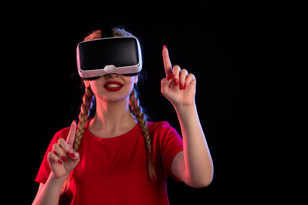 年轻女性在黑暗的墙上玩虚拟现实的年轻女性的画像人物黑色虚拟
