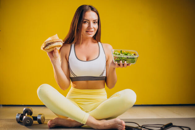 欧洲在黄色背景上吃沙拉的女人素食主义者食物运动