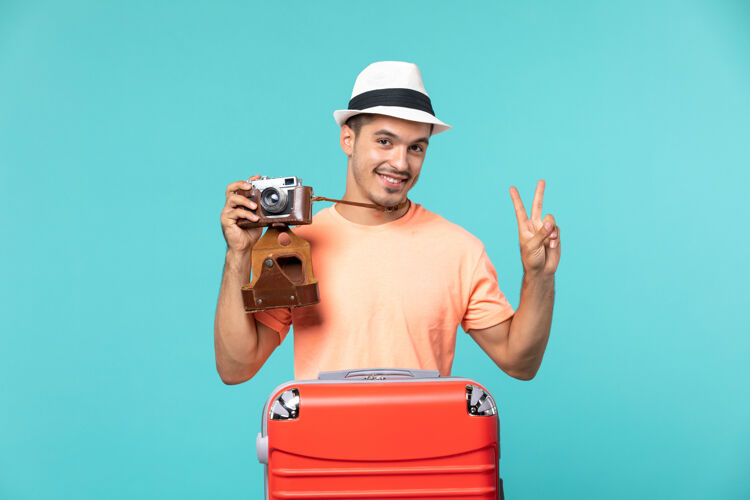 男性带着红色手提箱的度假男人用蓝色的相机拍照相机旅行采取