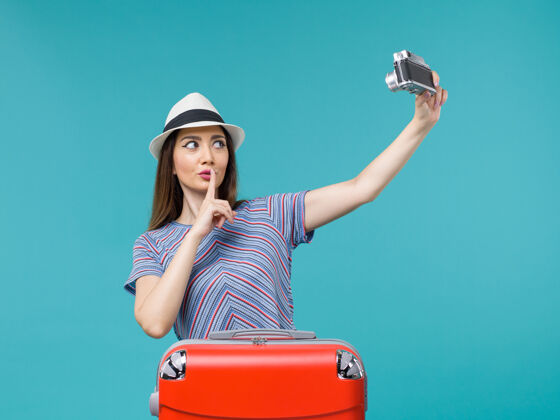 人度假的女人拿着相机在蓝色上拍照手提箱蓝色行李