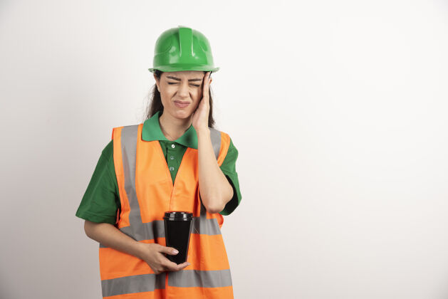 女女建造师用杯子碰她的头高质量的照片头盔控股工人