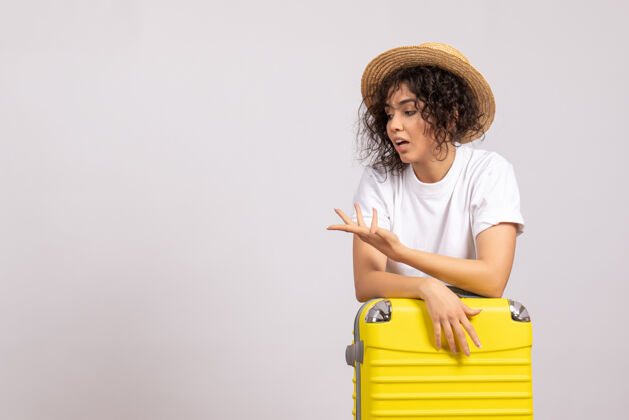 包正面图年轻女性带着黄色的包准备乘坐白色背景色的航班旅行度假阳光休息游客休息美丽微笑